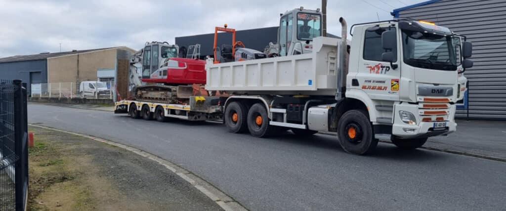 Camion DAF M2TP transportant une pelle rouge sur semi-remorque et équipement TP. Contact: 22150 ST CARRIVOC, 06.77.87.06.71.